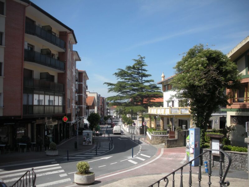 Vista de una calle con edificios de pisos en un lado y en el otro chalets