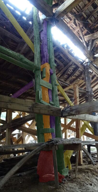 Estructura de vigas y postes de madera con algunos de ellos pintados con diferentes colores
