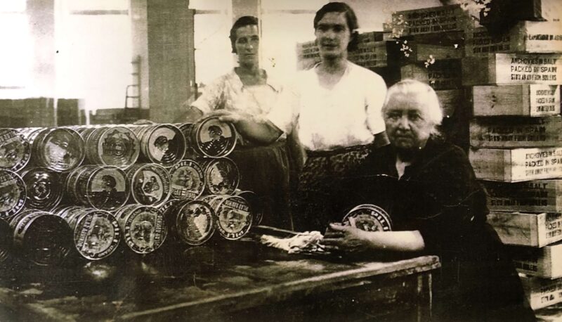 Fotografía antigua en blanco y negro de tres mujeres en una fábrica de conservas