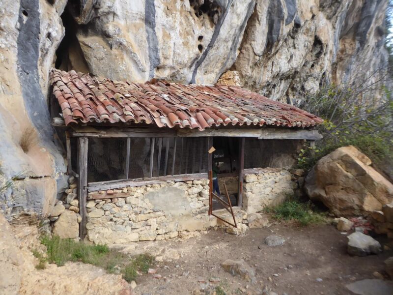 Tejabana con estructura de madera, cierres de piedra y tejado a una vertiente. Se inserta en una pared de una montaña