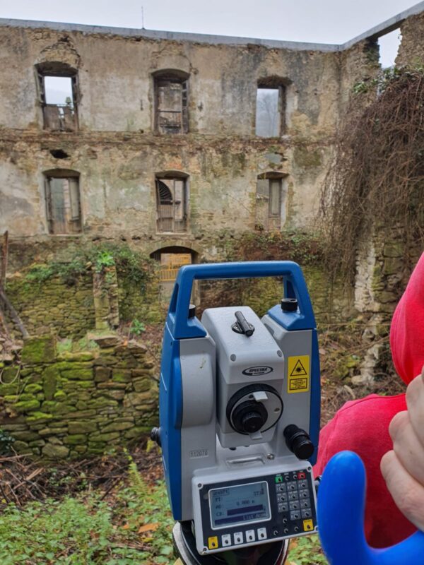 Interior de un edificio en ruinas. En primer término hay un instrumento de topografía (estación total)